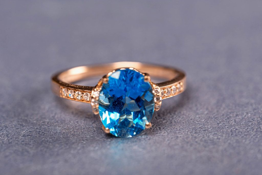 Gold ring with blue topaz on a purple background