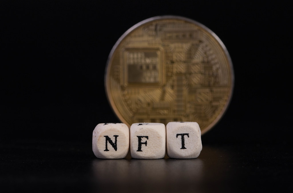 Golden coin ans wooden cubes with NFT text on black background