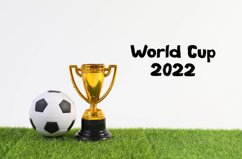 Golden trophy and ball with World Cup 2022 text on green grass