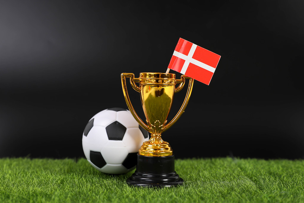 Golden trophy and football ball with flag of Denmark