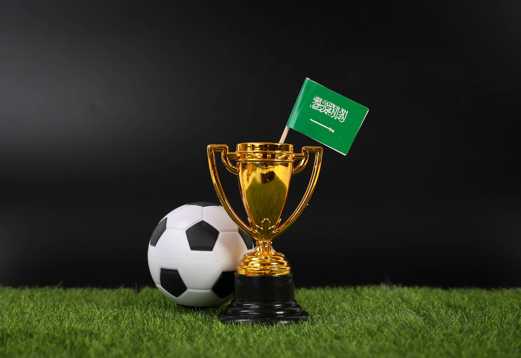 Golden trophy and football ball with flag of Saudi Arabia