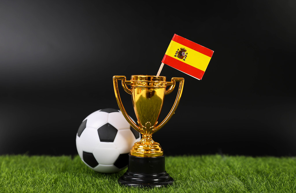 Golden trophy and football ball with flag of Spain
