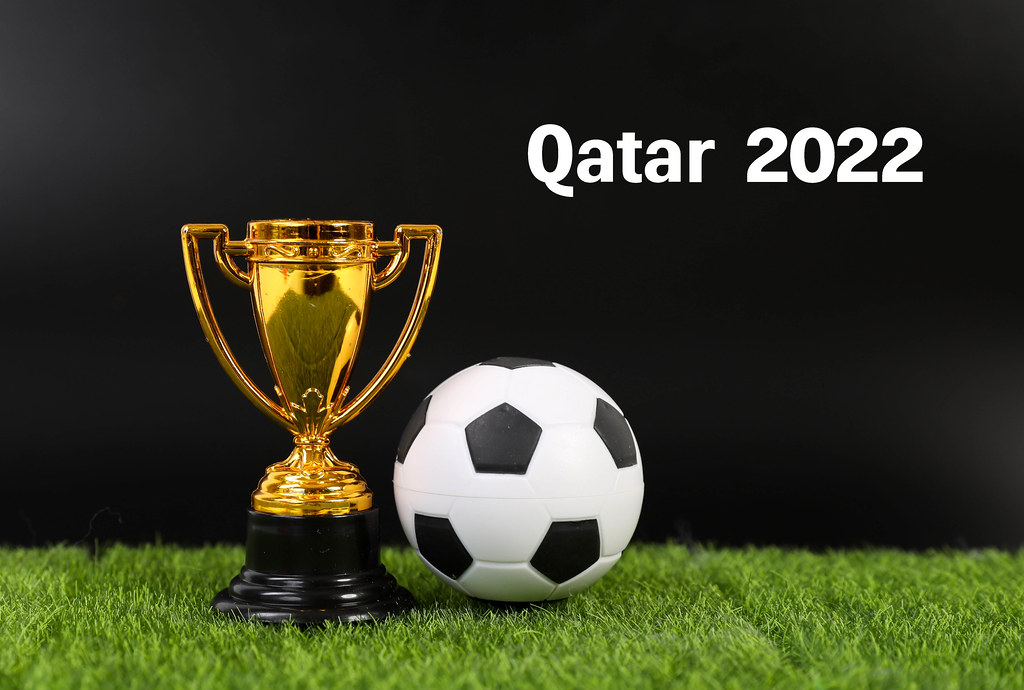 Golden trophy and football ball with Qatar 2022 text