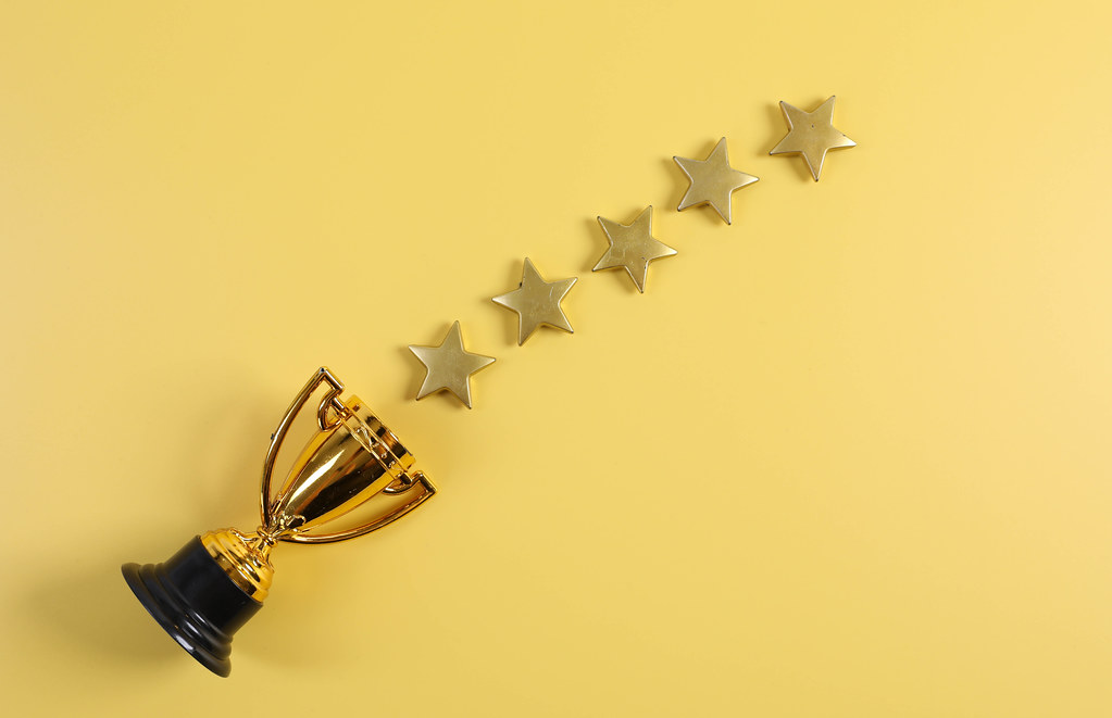 Golden trophy with five stars on yellow background
