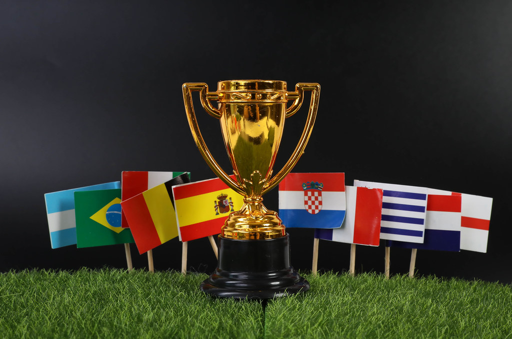 Golden trophy with national flags on grass