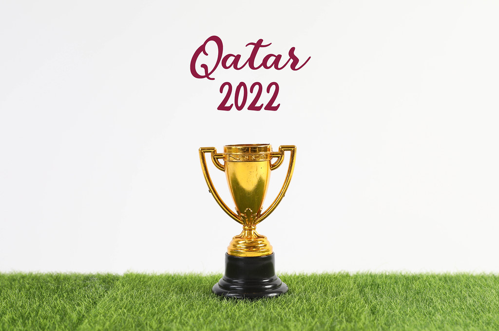 Golden trophy with Qatar 2022 text on green grass