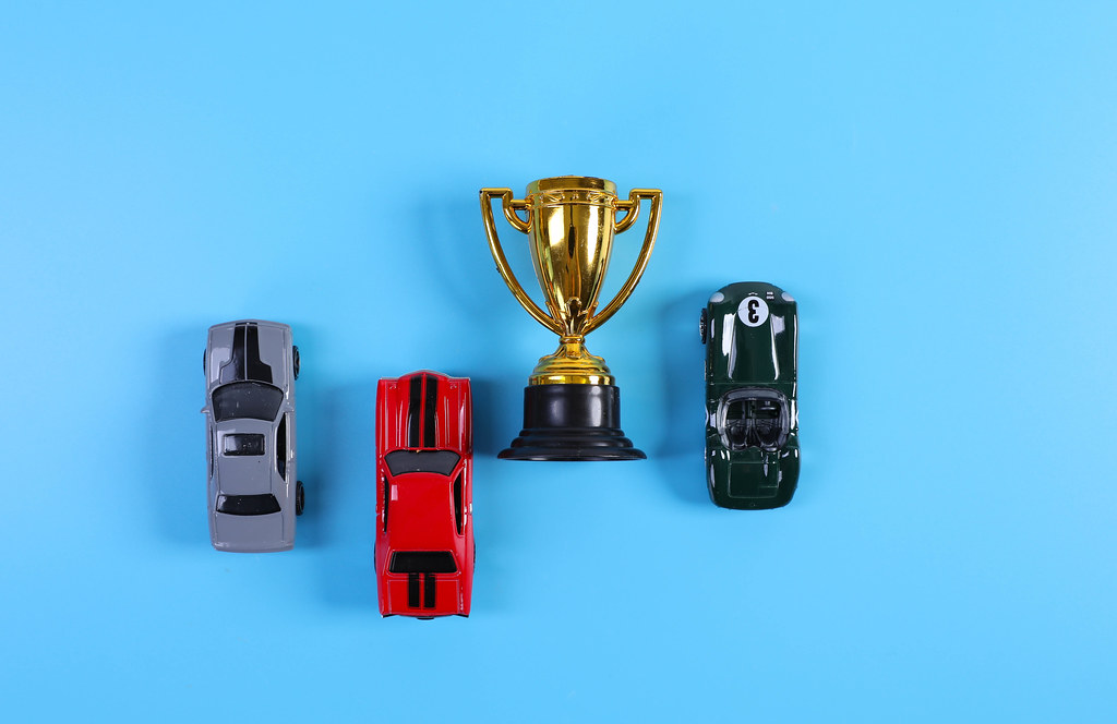 Golden trophy with toy racing cars on blue background