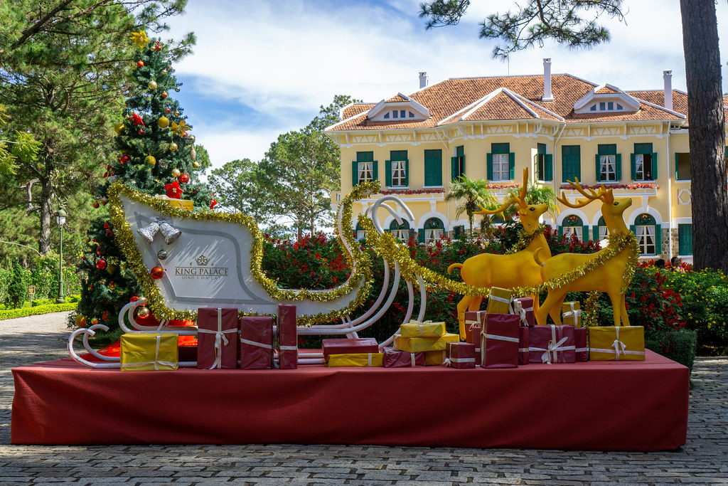 Goldene Rentiere, Weihnachtsbaum, Schlitten und Geschenke als Weihnachtsdekoration vor dem Bao Dai Königspalast in Da Lat, Vietnam