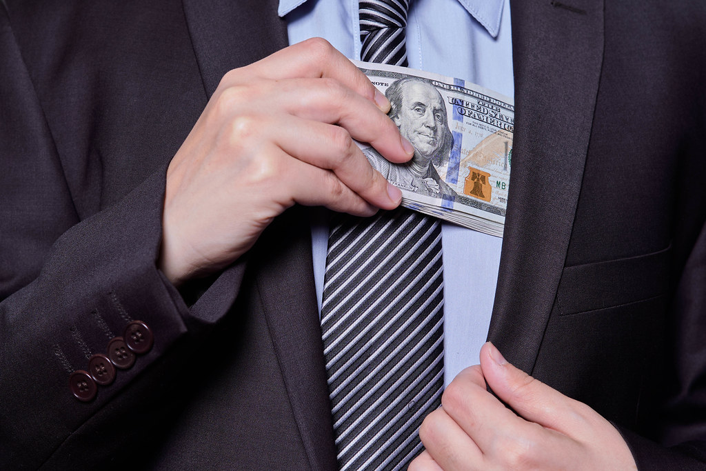 Government official slipping a stack of cash into his suit pocket