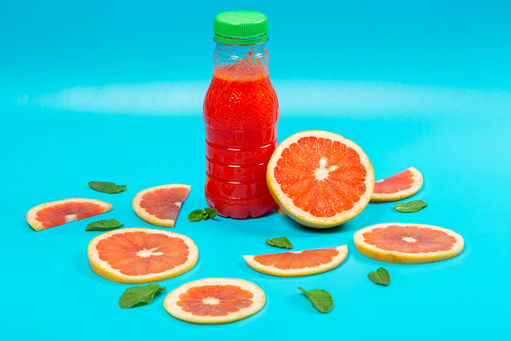 Grapefruit juice and ripe grapefruits on a blue background