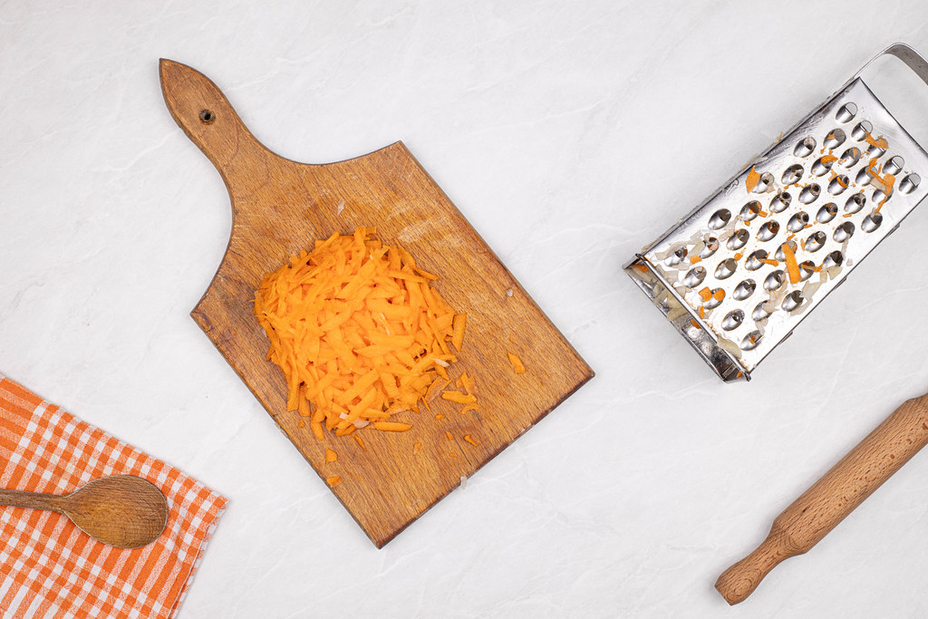 Grated Carrots with kitchen utensils on the table