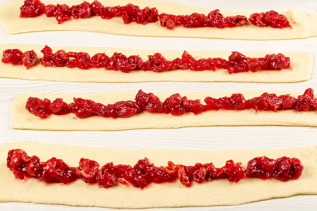 Gray dough strips with cherries, homemade baking concept