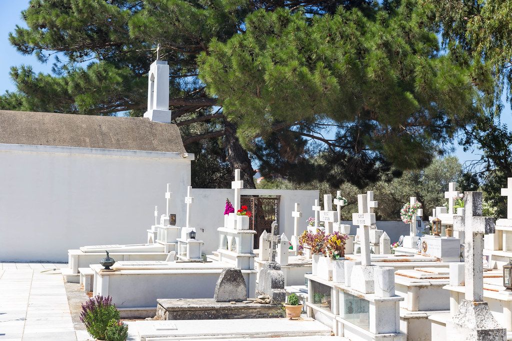 Greek cemetery on Naxos with marble tombstones, crosses and chapel surrounded by pine trees