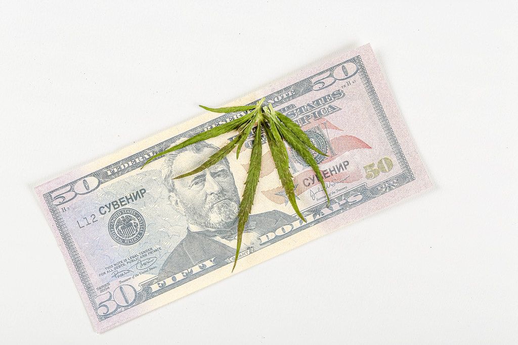 Green cannabis leaf on dollar bill, top view