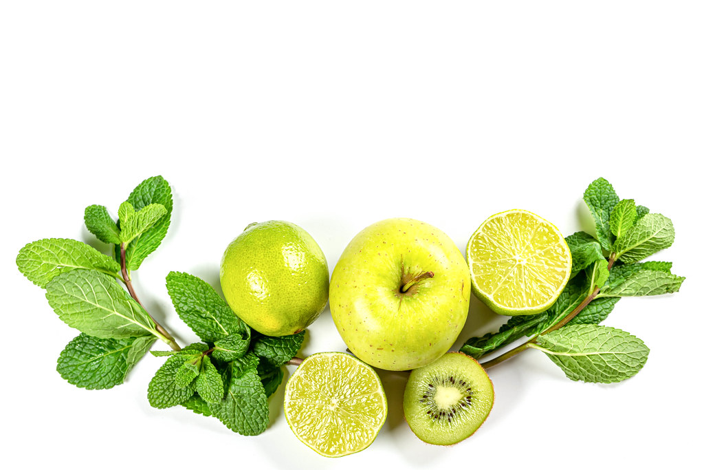 Green fruits and sprigs of mint on white, top view