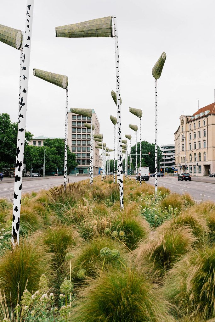 Green island of urban forrest with artificial birch pillars, green plants and wind vanes
