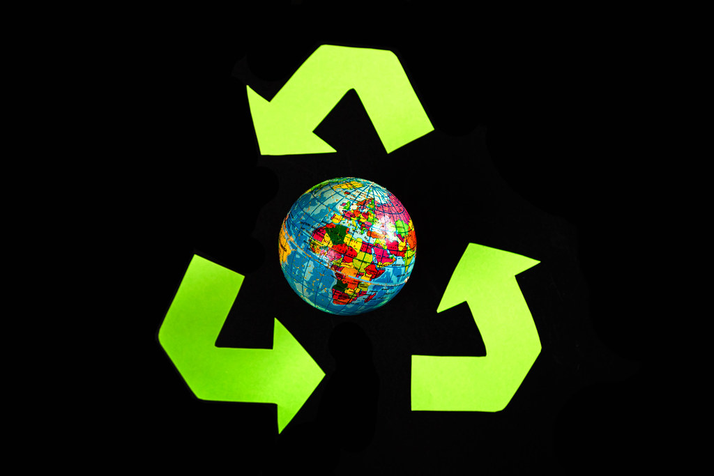 Green recycle eco symbol and globe on dark background
