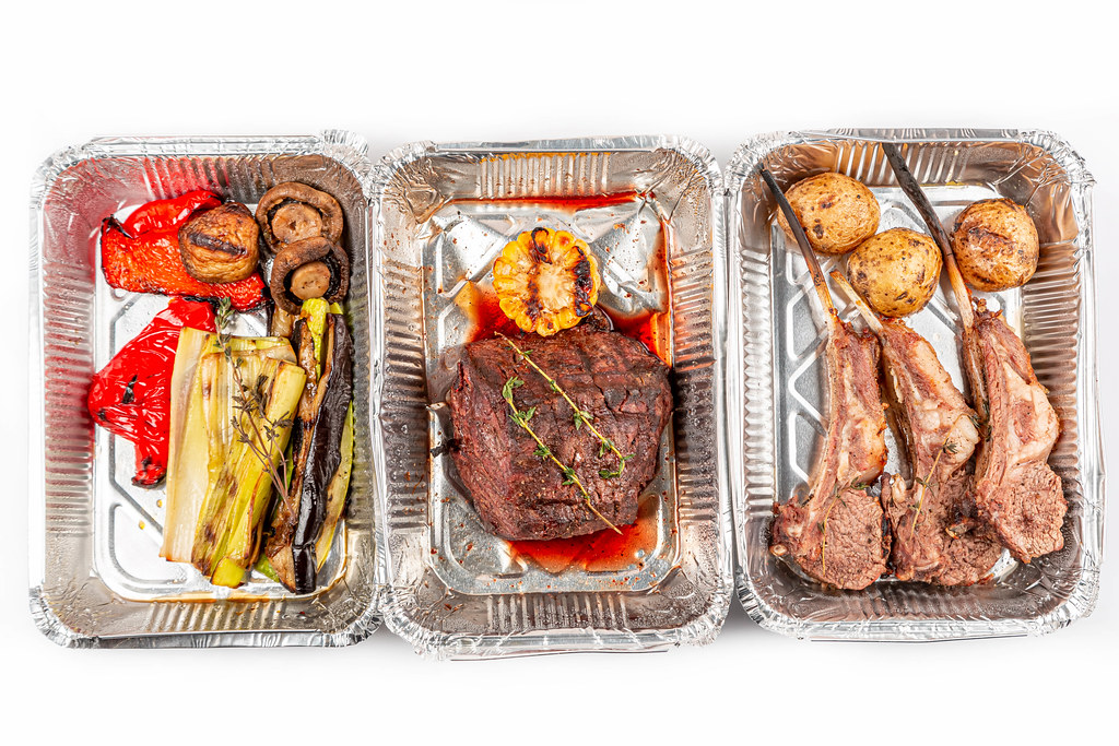 Grilled vegetables, filet mignon and lamb ribs in containers, top view