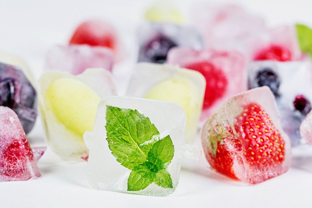 Group of berries and mint, frozen inside ice cubes