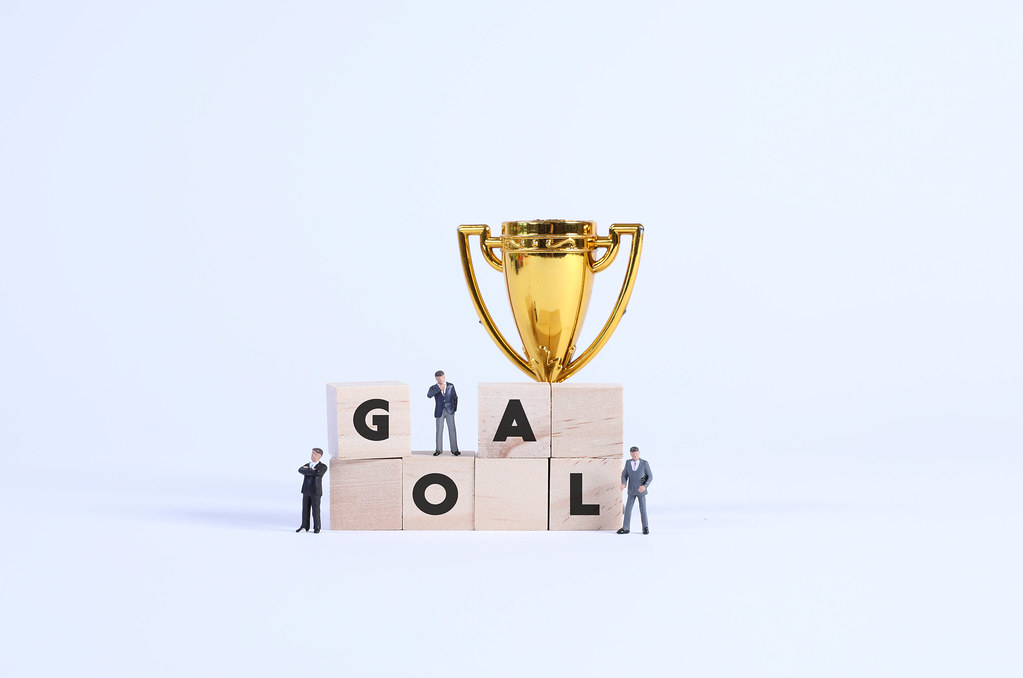 Group of businessman with golden trophy and wooden blocks with Goal text