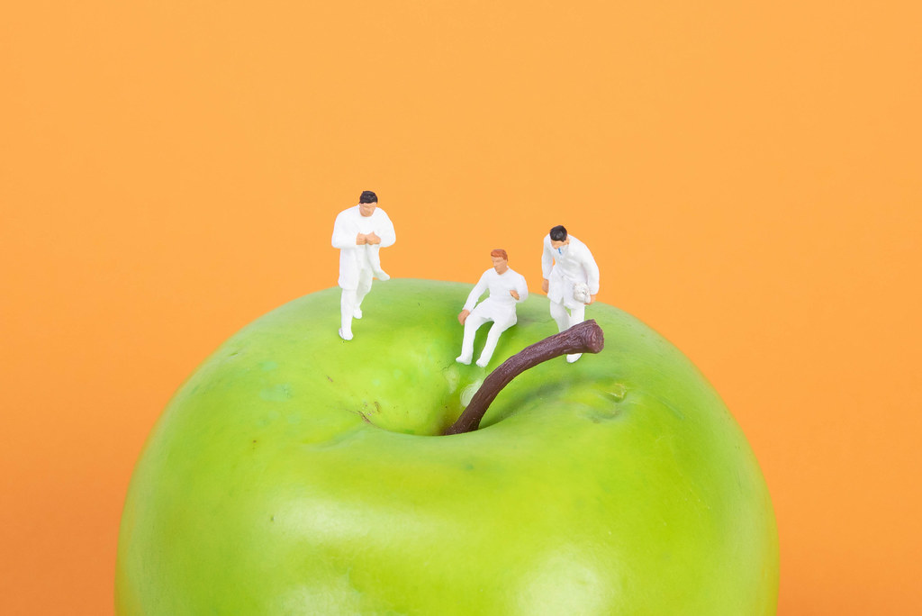Group of doctors sitting on a green apple