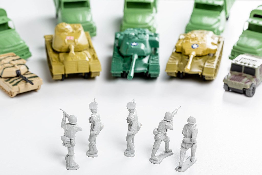 Group of plastic soldiers surrounded by enemy tanks and cars