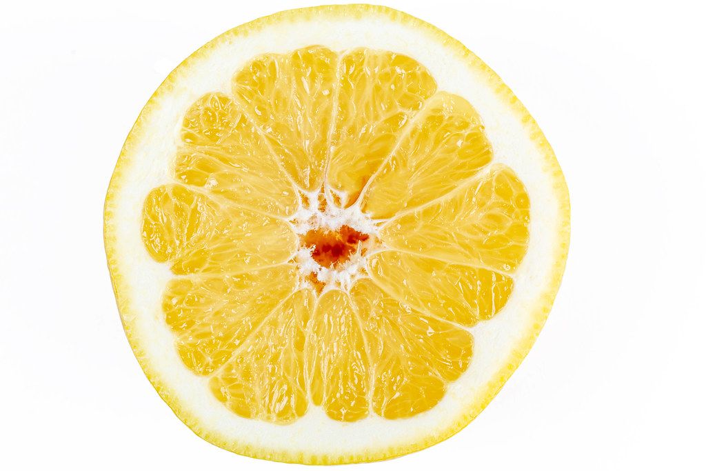 Half of a ripe yellow grapefruit on a white background