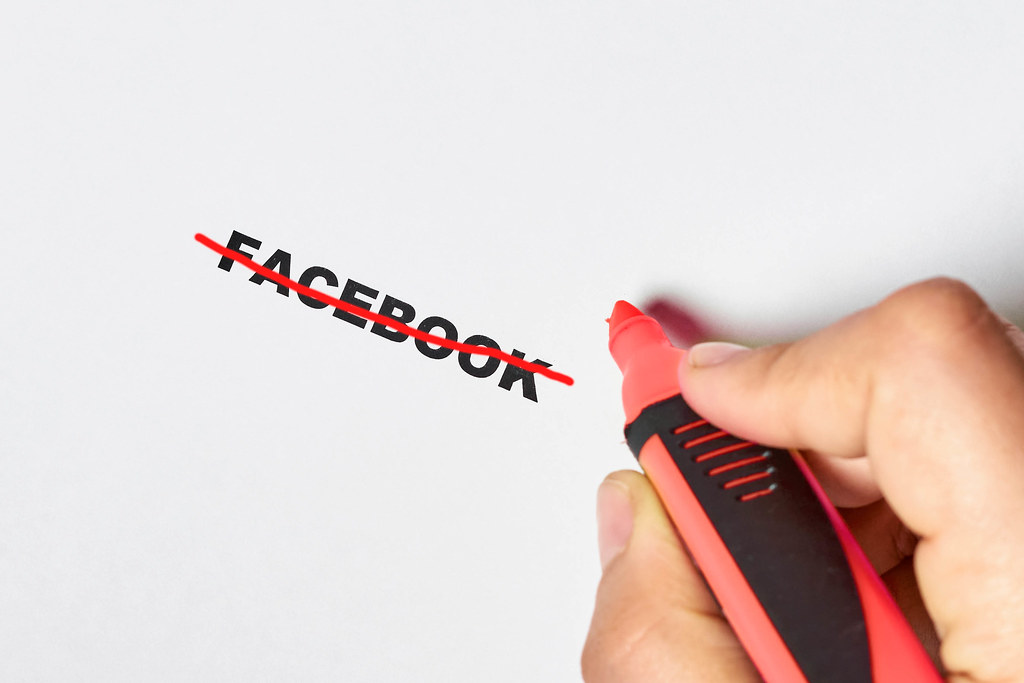 Hand crossing with line over Facebook - symbol of weak security of Facebook