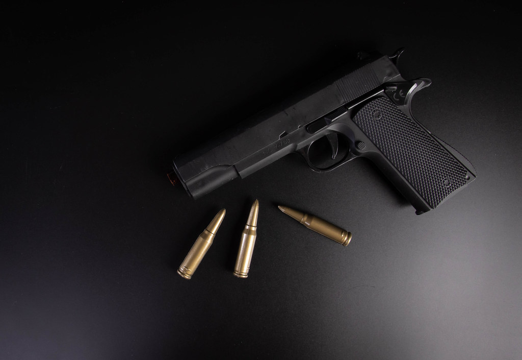 Hand gun with bullets on black background