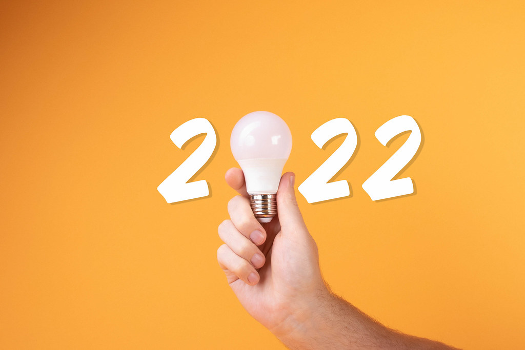 Hand holdign white lightbulb and 2022 text on yellow background