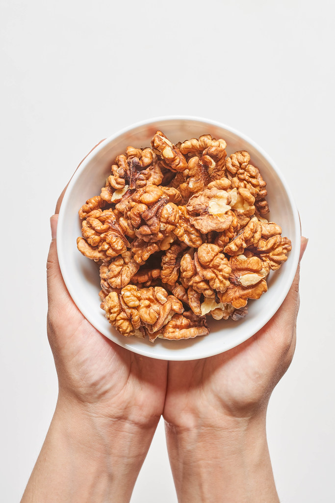 Hand holding a bowl of walnuts