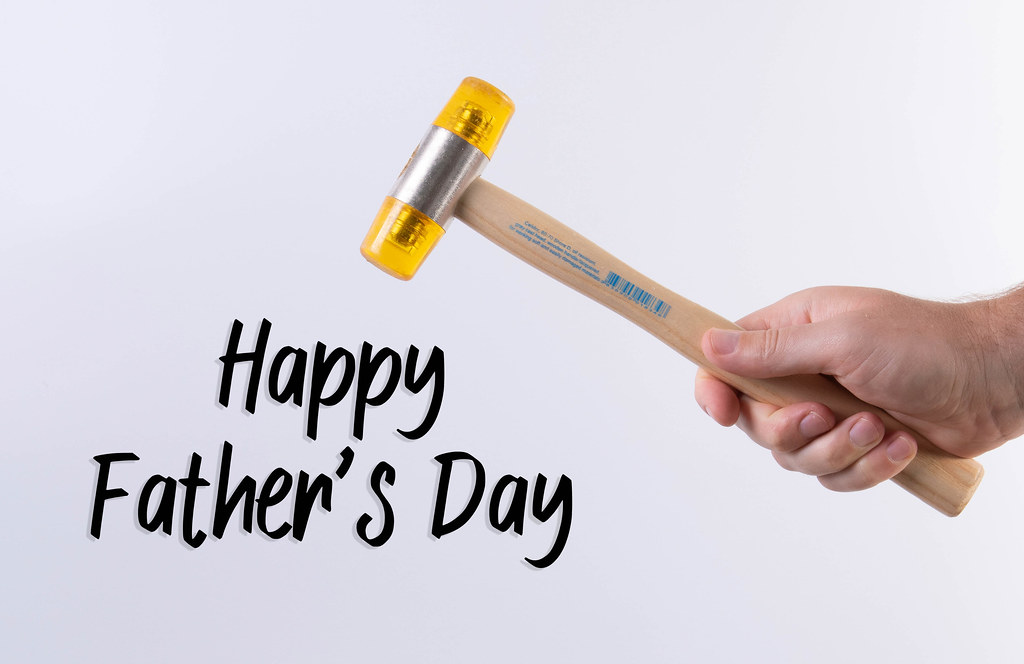 Hand holding a hammer and Happy Father's Day text