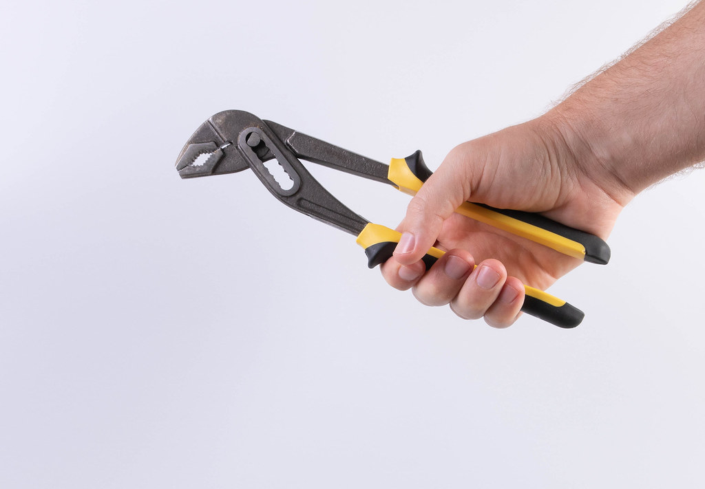 Hand holding adjustable pliers on white background