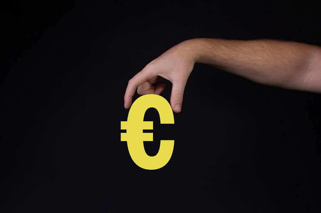 Hand holding Euro symbol on black background