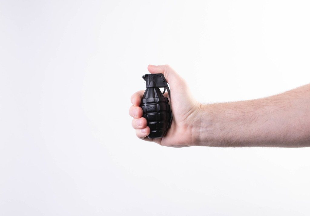 Hand holding hand grenade on white background