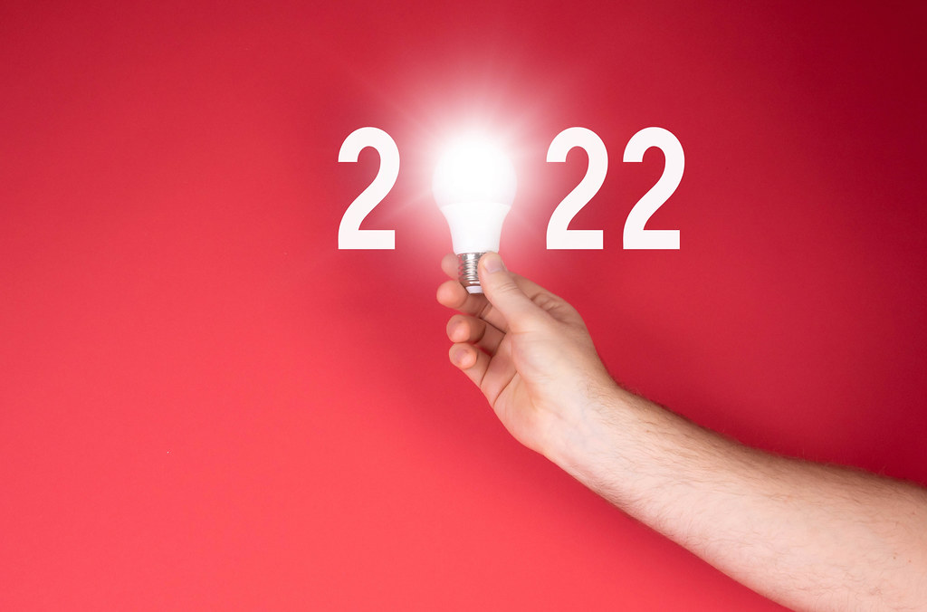 Hand holding lightbulb and 2022 text on red background
