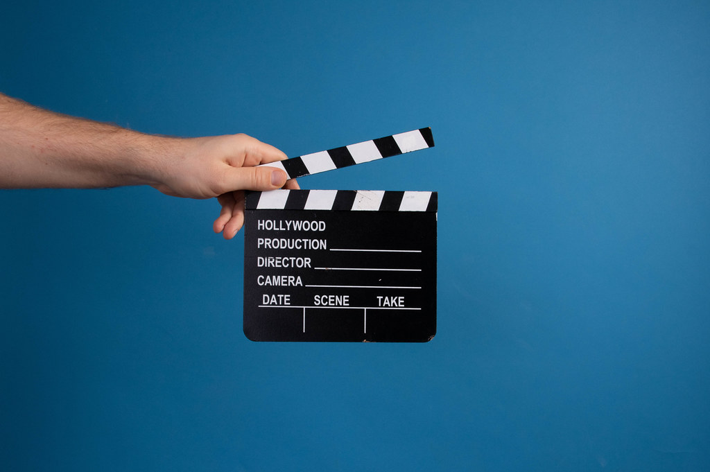 Hand holding movie clapper over blue background