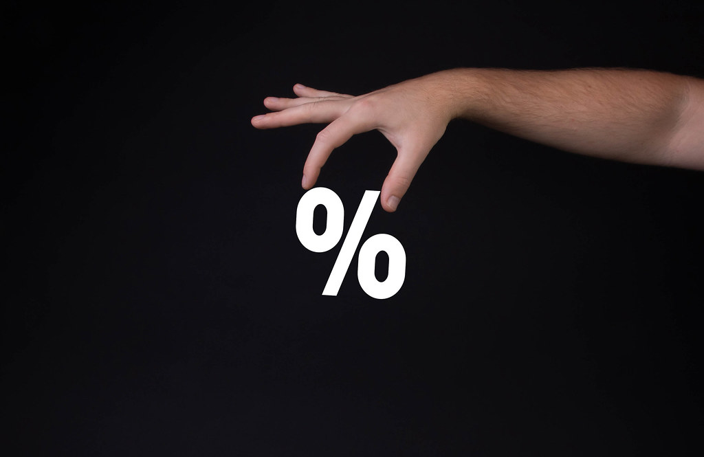 Hand holding percentage symbol on black background