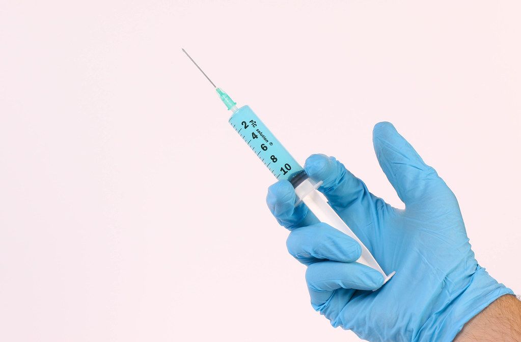 Hand holding syringe with blue fluid