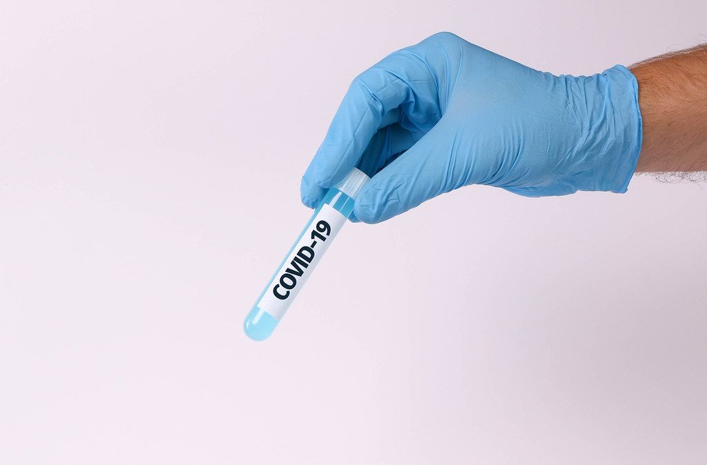Hand holding test tube with text COVID-19
