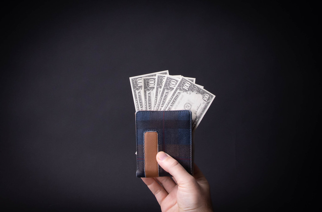 Hand holding wallet with dollar money on black background