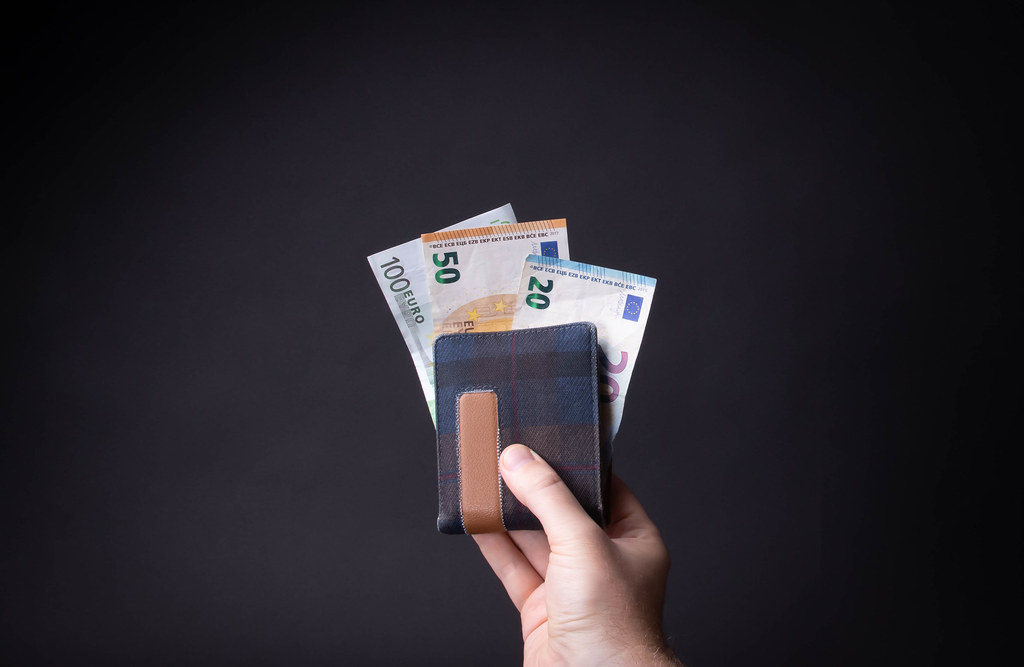 Hand holding wallet with Euro money on black background