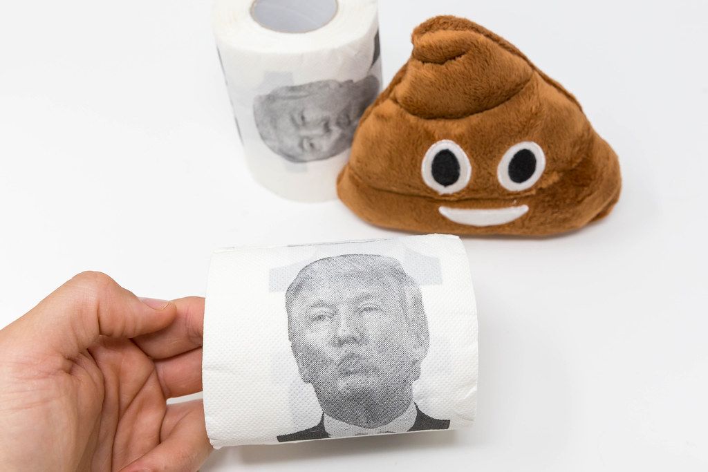 Hand holds a loo roll with Donald Trump