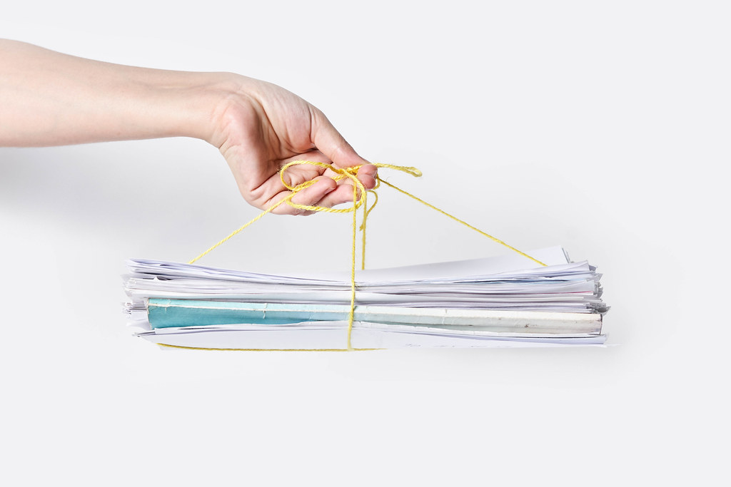 Hand holds a stack of recycling paper against white background