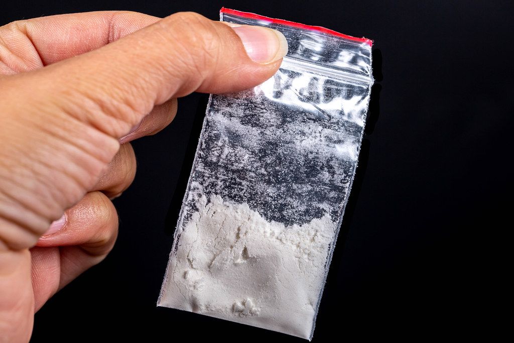 Hand holds plastic packet with drugs. Concept drug abuse and danger addiction