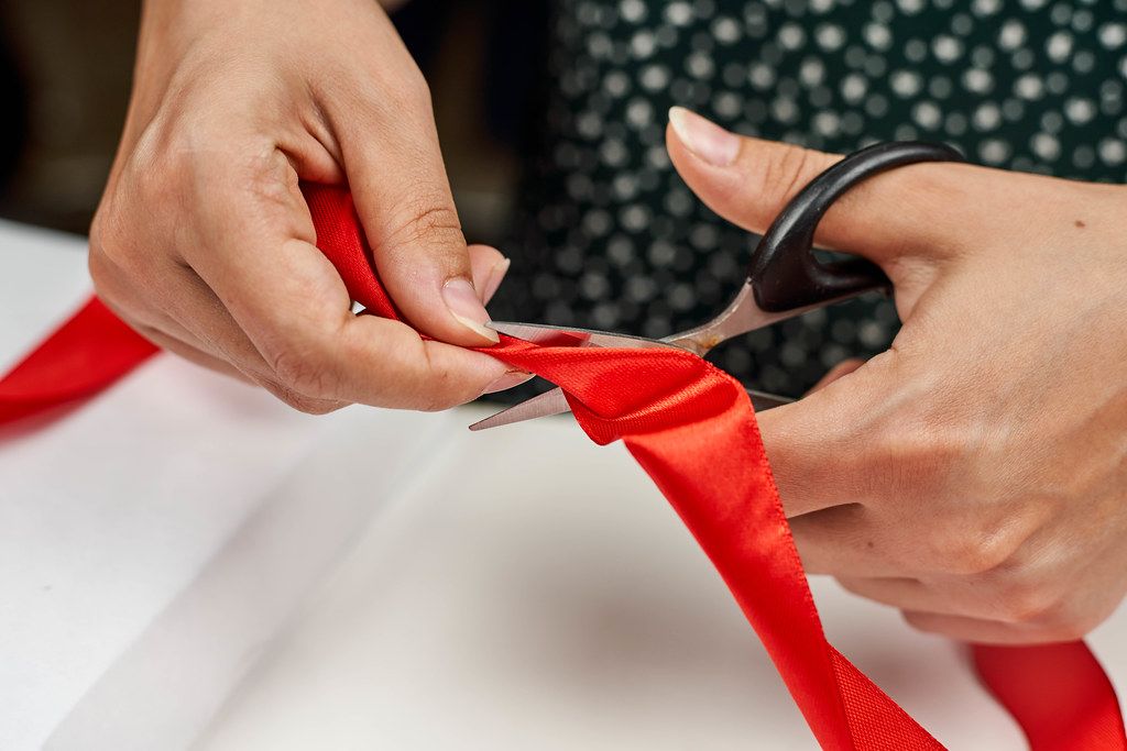 Hand of a woman cutting the ribbon by Christmas present at table