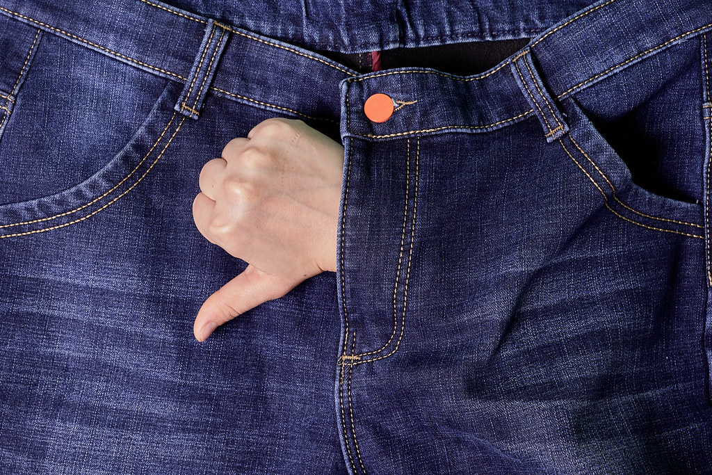 Hand of person with thumbs down hand gesture from jeans - symbol male of sexual problems
