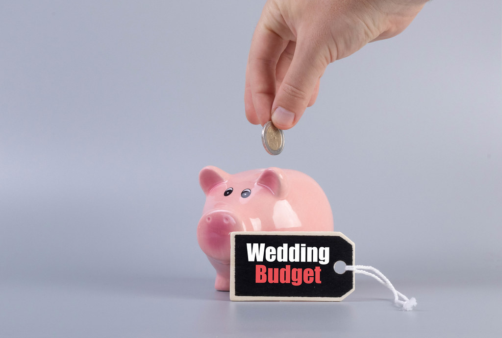 Hand putting coin in a piggybank and Wedding Budget text