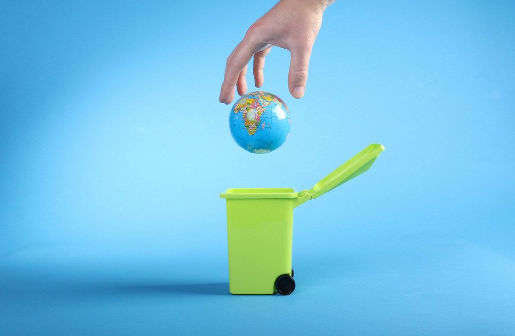 Hand throwing globe into trash can