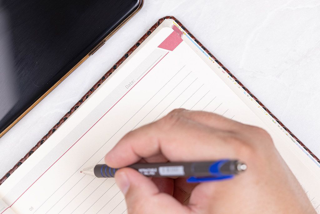 Hand with Pencil above Paper Notebook with Business concept